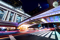 Long exposure at night of Grand Central Terminal and Pershing Square with cop cars and other traffic creating light trails with the Chrysler and MetLife buildings in the background