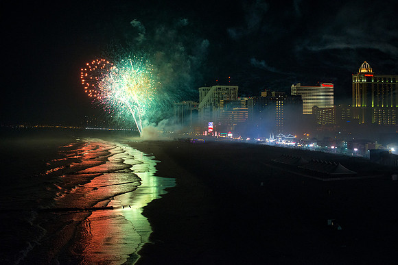 Photograph of the fireworks show over the Atlantic Ocean and Atlantic City boardwalk in New Jersey including the night sky and beach lit up at night