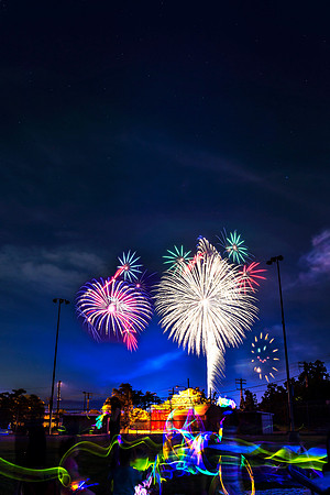 fireworks in the night sky over a baseball field in sleepy hollow, new york with light painting from glow sticks