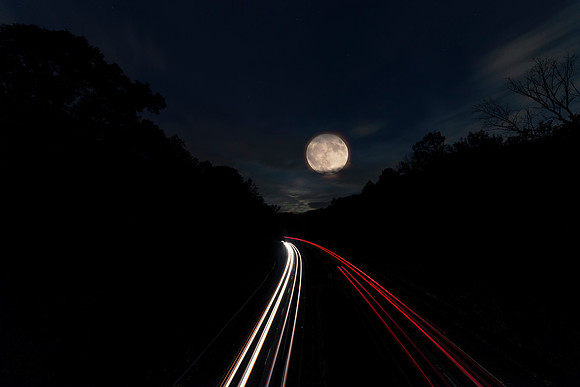 2019 Full Hunter's Moon over Rt. 117 with long exposure light trails from cars and woods on both sides in Sleepy Hollow, NY